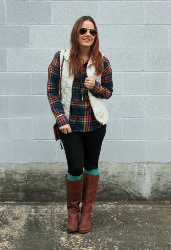 girl in the cold wearing vest, flannel, sunglasses, leggings and pair of brown boots and colorful knee socks