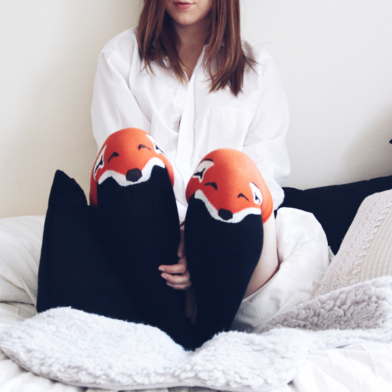 girl sitting in bed wearing fox thigh-highs, shorts, and a long-sleeved white collared shirt