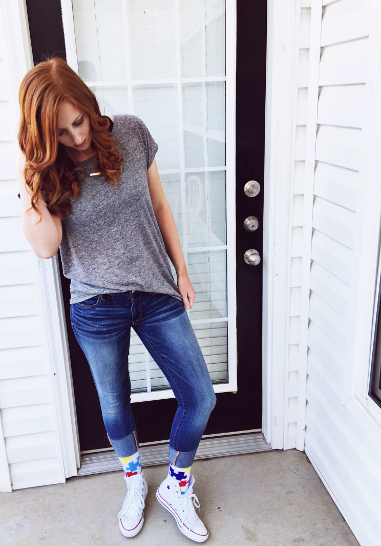 girl just outside door wearing casual outfit, gray t-shirt and socks under jeans