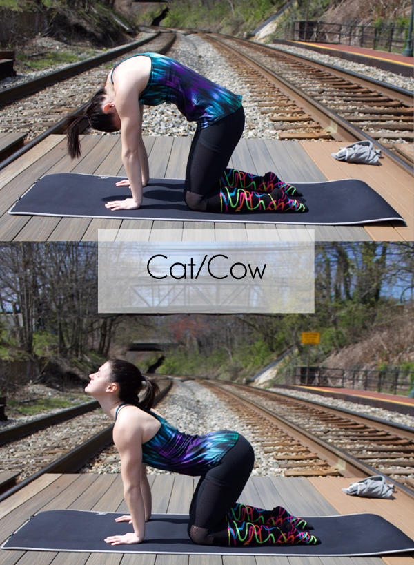 girl performing yoga poses for cat and cow wearing funky socks with railroad in the background
