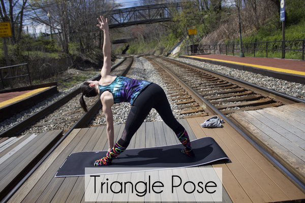 girl in the yoga triangle pose on mat wearing black yoga pants and funky knee highs